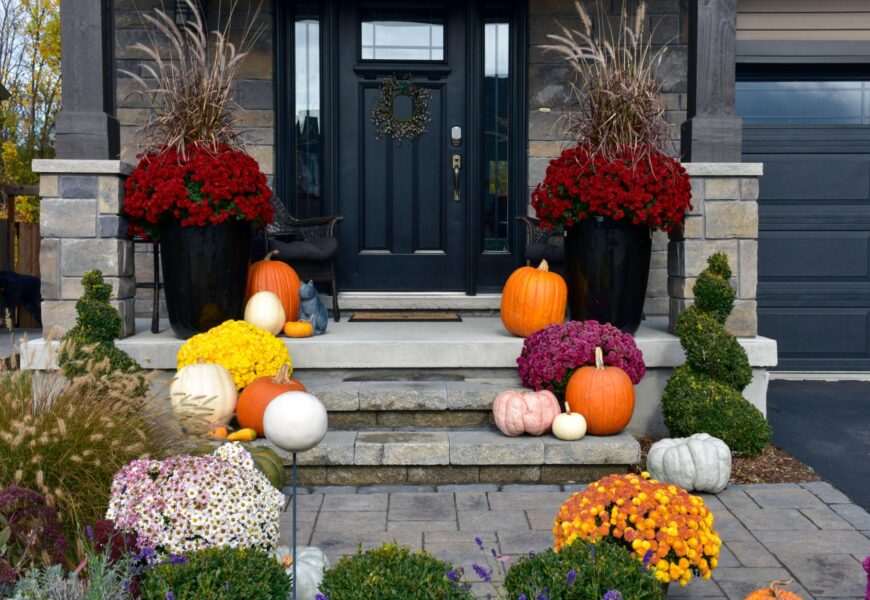 Fall porch decorating ideas with colorful mums, pumpkins, and potted plants arranged on front steps.