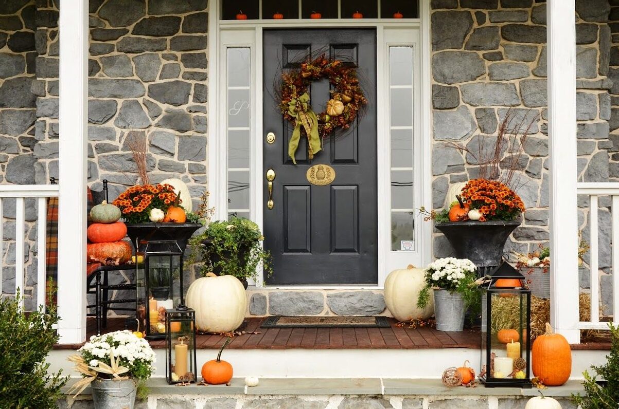 Rustic fall porch decorating ideas featuring pumpkins, mums, wreath, and farmhouse style entrance