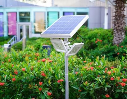 Solar powered outdoor garden light with panel on pole surrounded by vibrant flowers