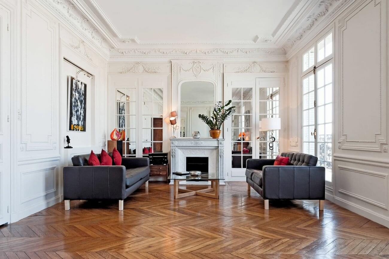 Elegant Parisian apartment living room with white paneled walls, high ceilings, and classic French interior design.