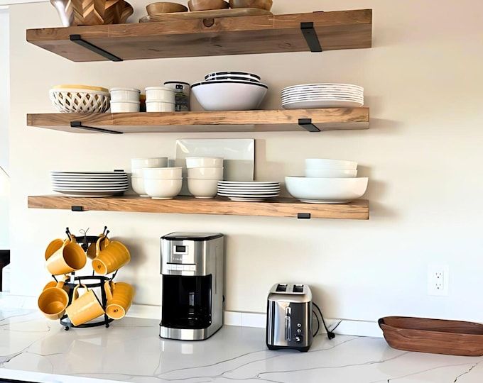 Minimalist kitchen shelf decor with floating wooden shelves, white dishes, coffee station, and modern styling accents.