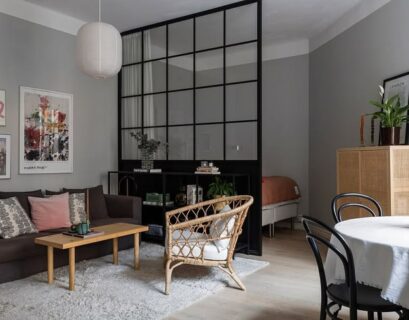 Modern apartment living room with black framed glass divider separating spaces in an open-plan layout.