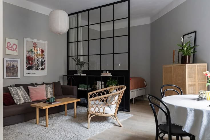 Modern apartment living room with black framed glass divider separating spaces in an open-plan layout.