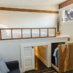 Tiny apartment loft bedroom with hidden storage under stairs and elevated sleeping area for small space living.