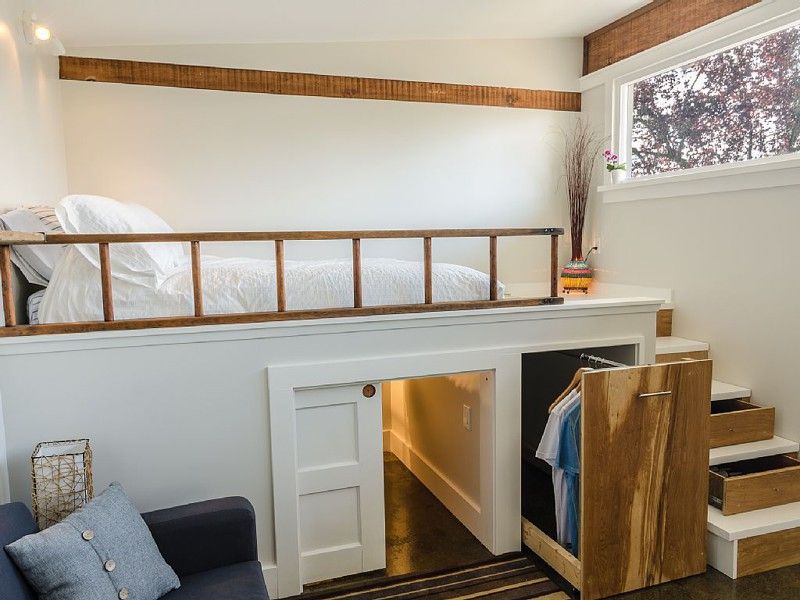 Tiny apartment loft bedroom with hidden storage under stairs and elevated sleeping area for small space living.