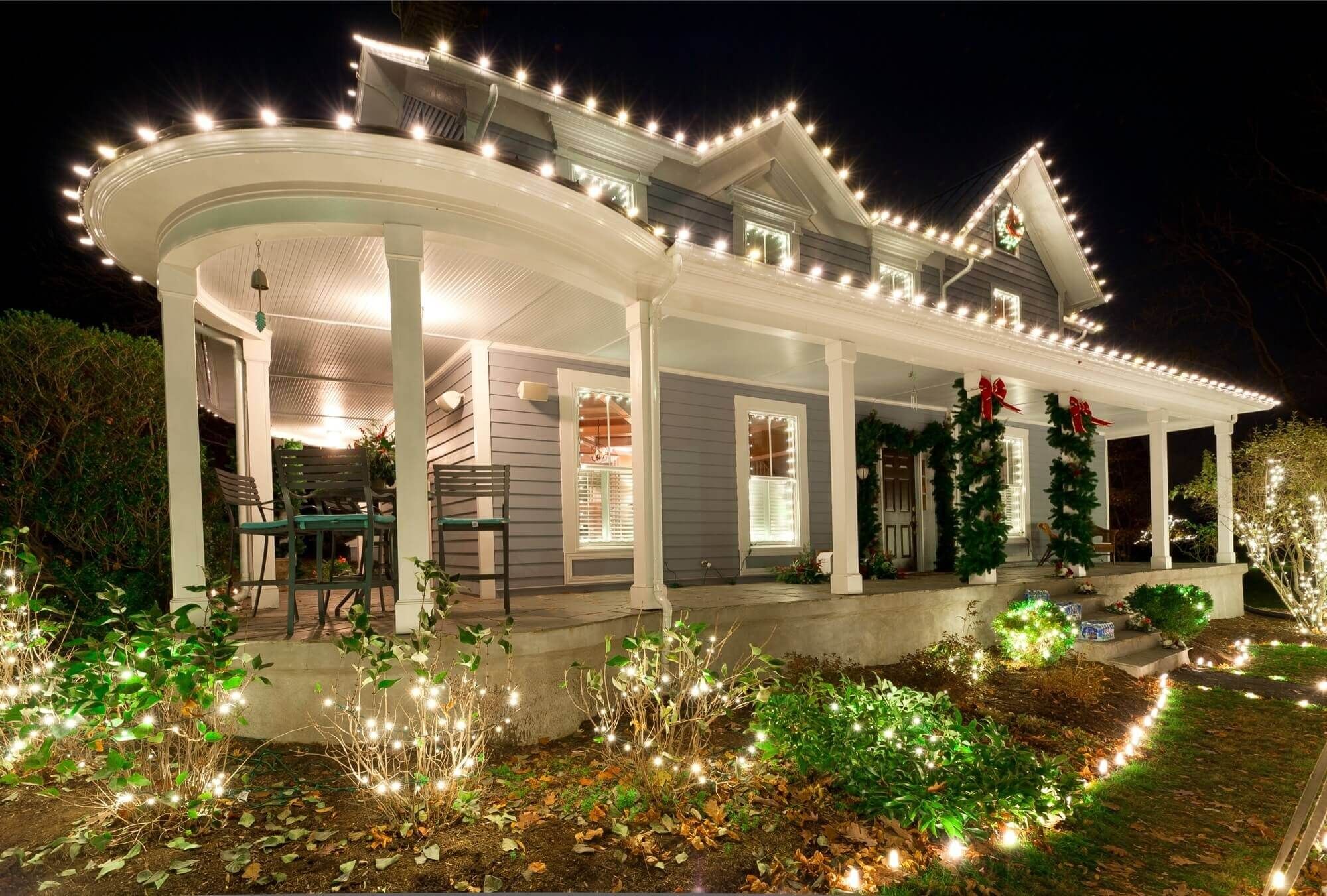 Beautifully decorated house exterior with glowing winter lights and elegant January landscaping at night.