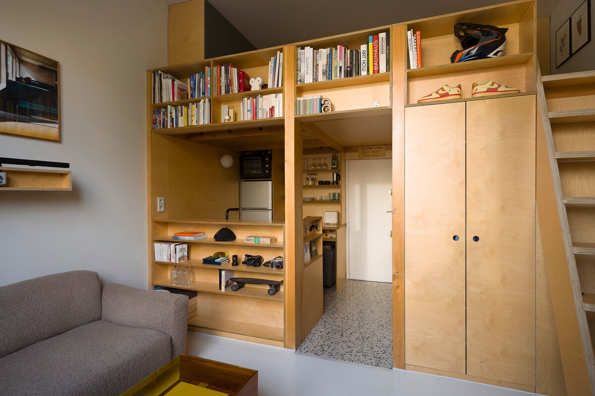 Small apartment workspace with built-in shelves, desk, and compact storage furniture for efficient organization.