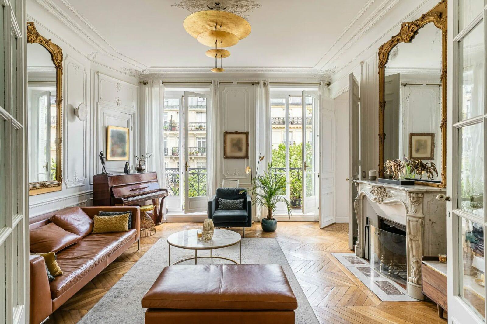 Sophisticated Parisian living room with gold mirrors, classic fireplace, and elegant French apartment decor.