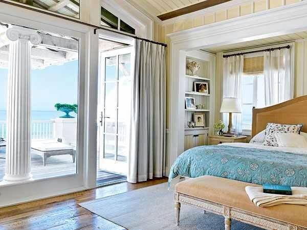 Bright coastal bedroom with ocean views, light wood furniture, and airy blue and white bedding.