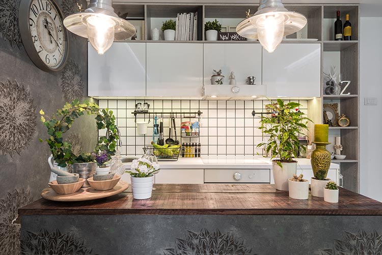 Contemporary kitchen shelf decor with plants, decorative bowls, lighting, and stylish open shelving above countertops.
