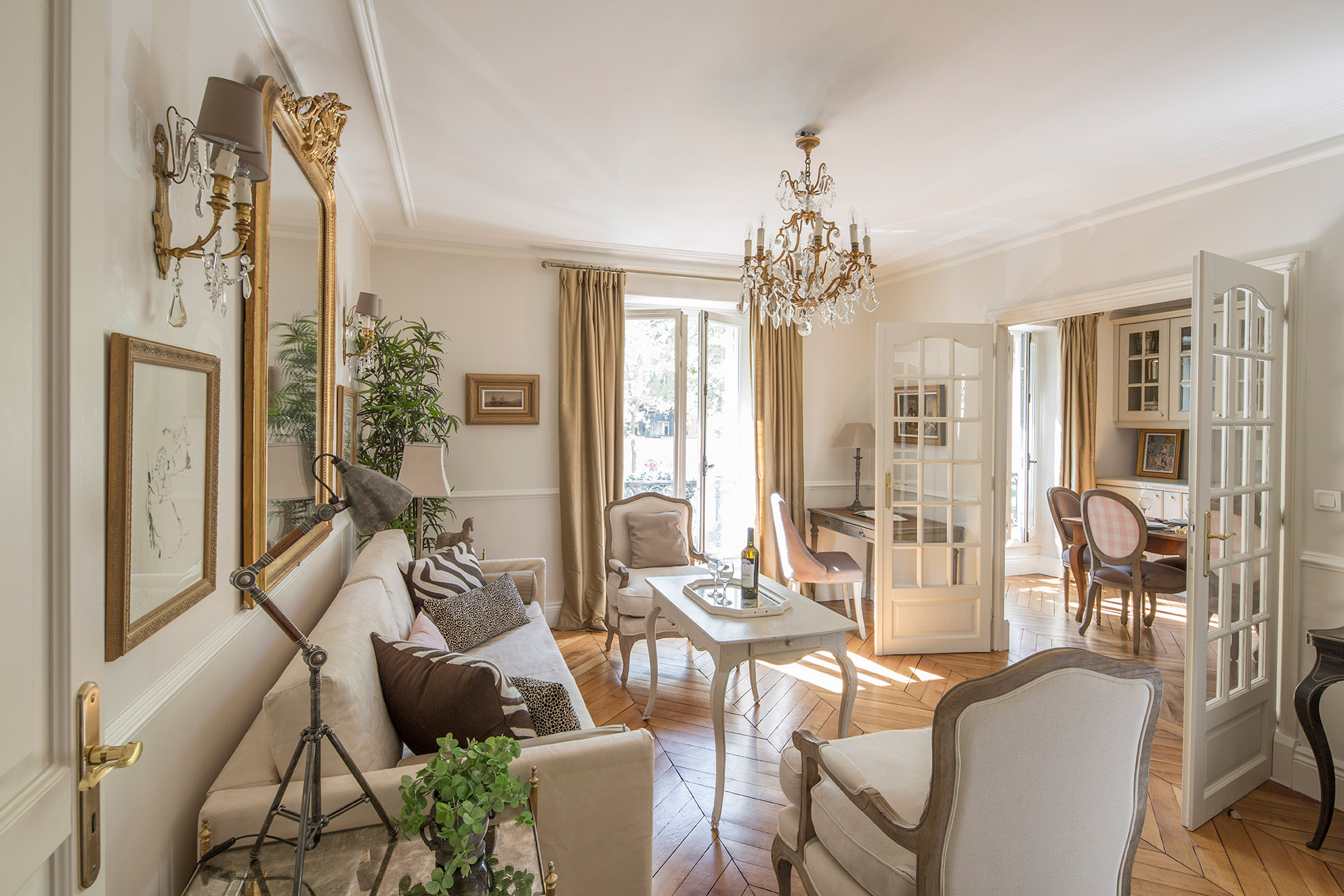 Parisian apartment style : Bright dining and living area with elegant chandeliers, neutral decor, and French-inspired details.
