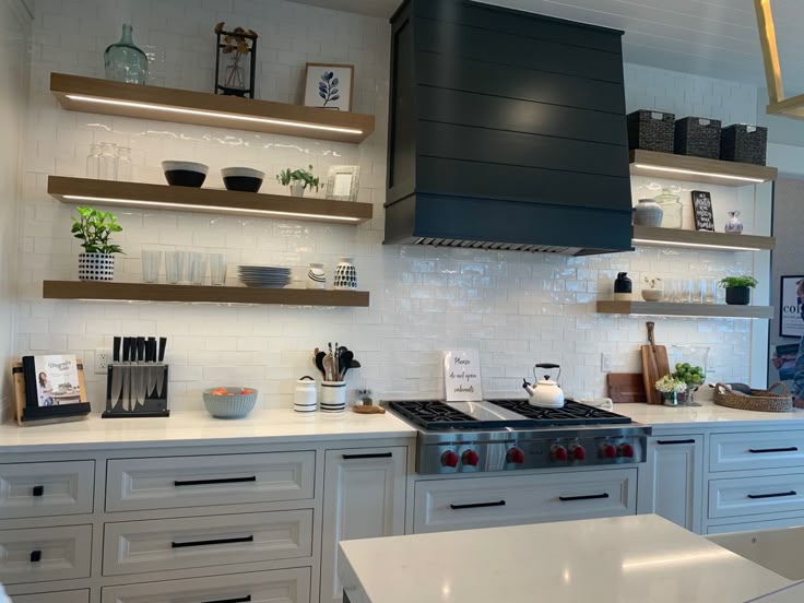 Luxury kitchen with floating shelves, dark cabinets, modern lighting, and elegant open shelf styling ideas.