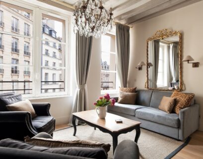 Chic Parisian apartment living room with tall windows, neutral furniture, and luxurious French interior styling.