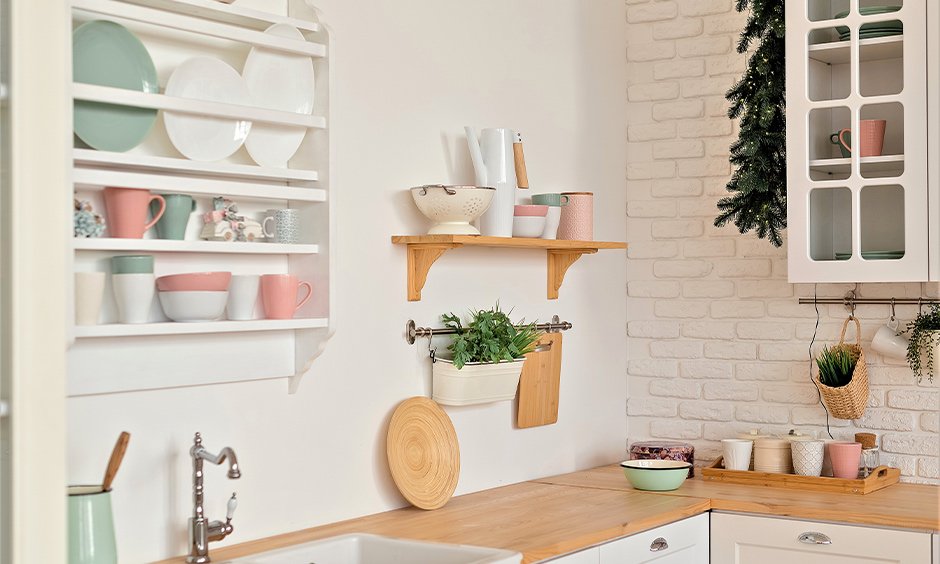 Small kitchen with open shelf decor, pastel dishes, plants, and space-saving organization ideas.