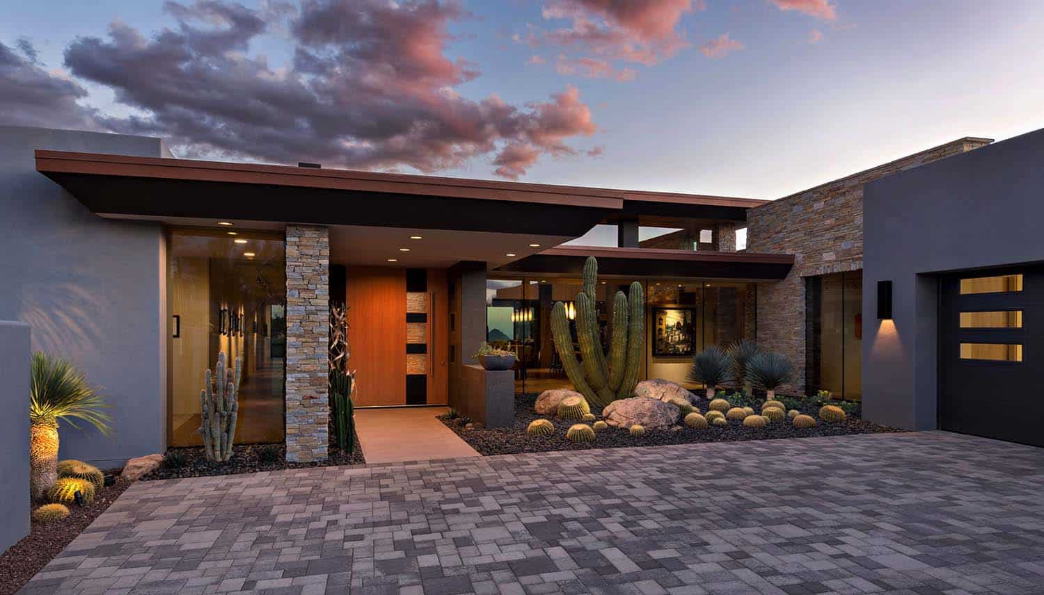 Desert modern house exterior with warm lighting, stone pathways, and minimalist outdoor design