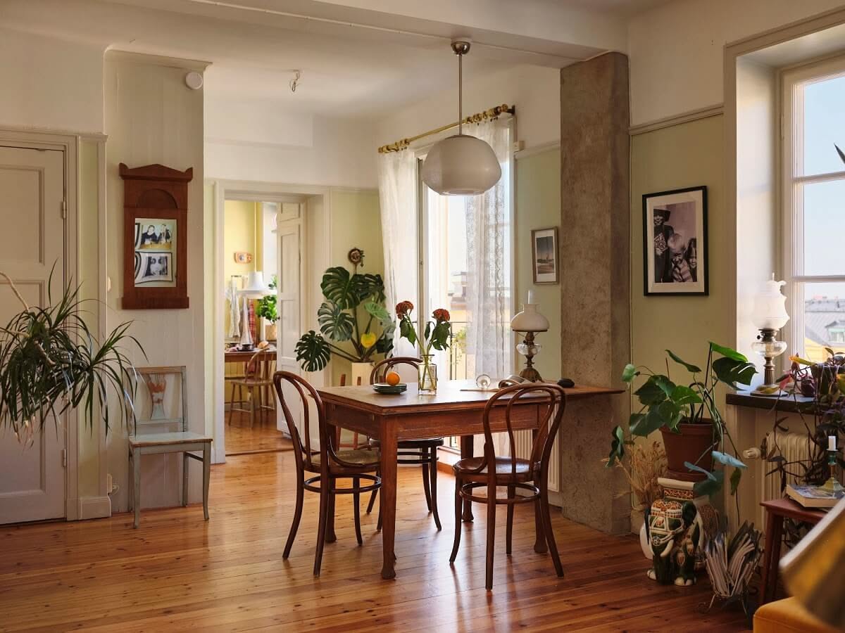 Small vintage apartment dining area with wooden table, natural light, and classic home decor