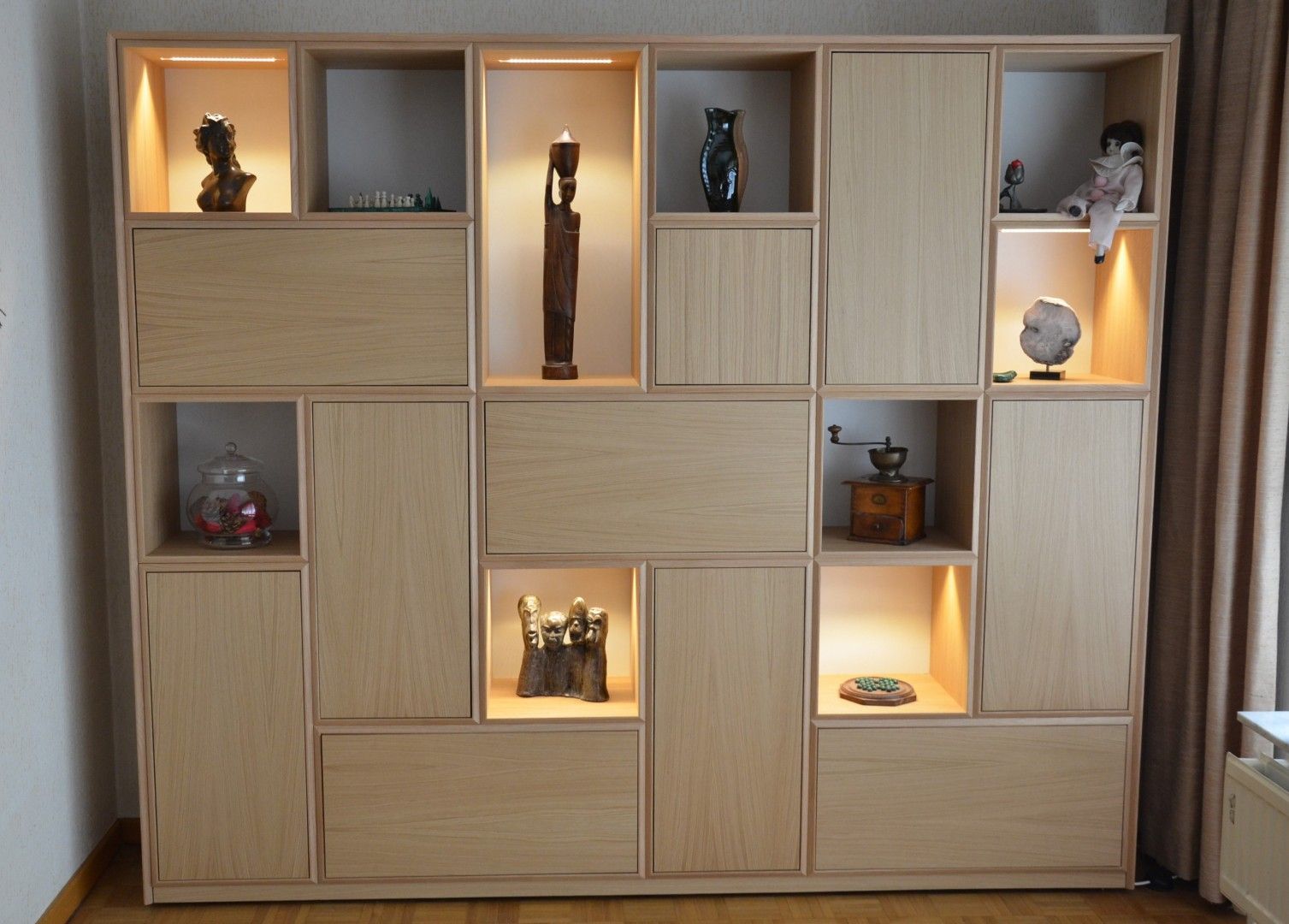 Contemporary apartment wall unit with decorative shelves, hidden storage, and illuminated display compartments.