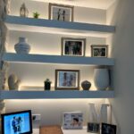 Modern floating wall shelves with LED lighting and decorative frames in a living room