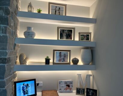 Modern floating wall shelves with LED lighting and decorative frames in a living room