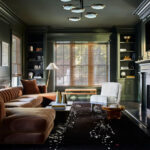 Dark green moody living room with fireplace, classic furniture, and cozy atmospheric lighting