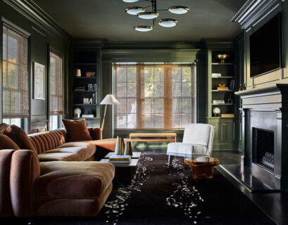 Dark green moody living room with fireplace, classic furniture, and cozy atmospheric lighting